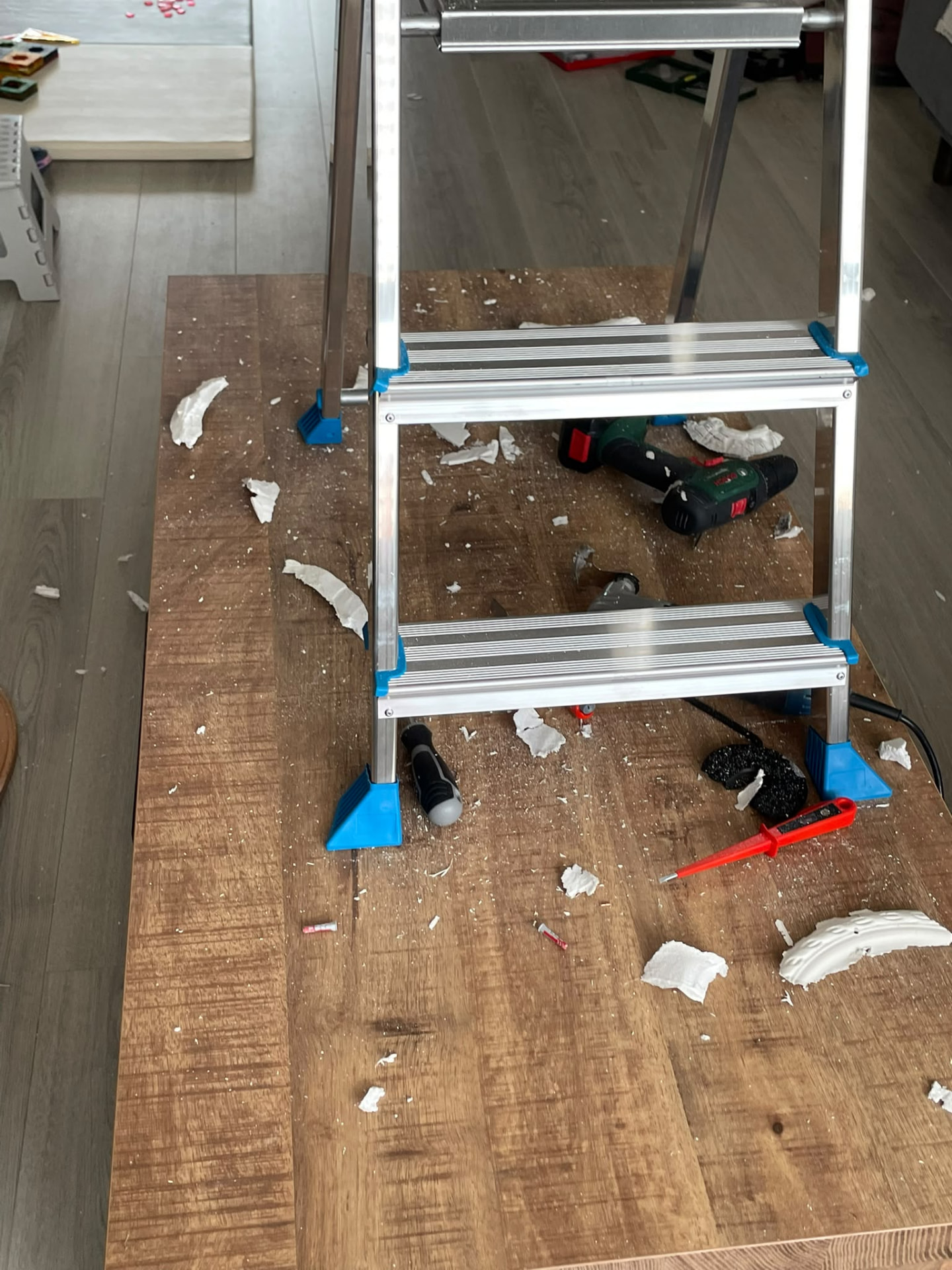 Werkplek met trapje en gereedschap tijdens het ophangen van de plafondlamp
